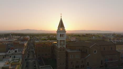 Pull-back-footage-of-nice-square-tower-against-rising-sun.-Backwards-fly-above-city-in-morning.-Rome,-Italy