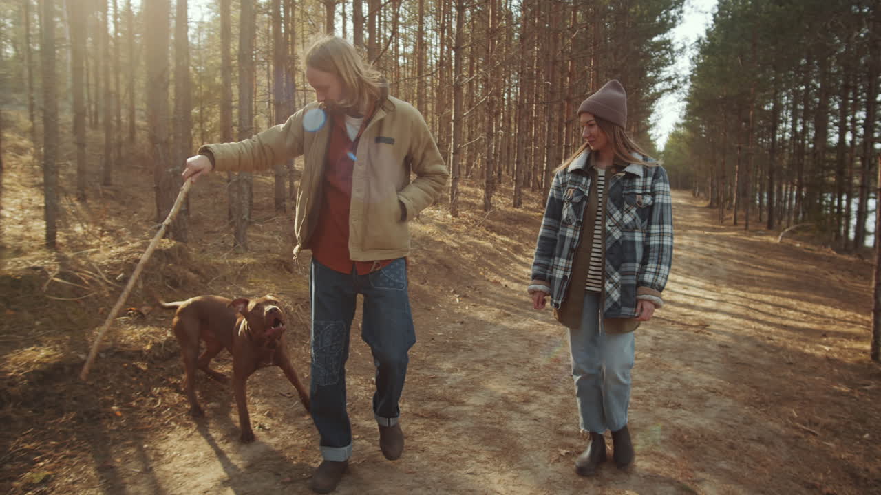 pareja caminando por el bosque y jugando con el perro
