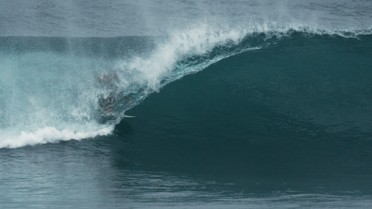 Surfer carves line inside large tube, wave wall wraps tightly around rider in perfect barrel
