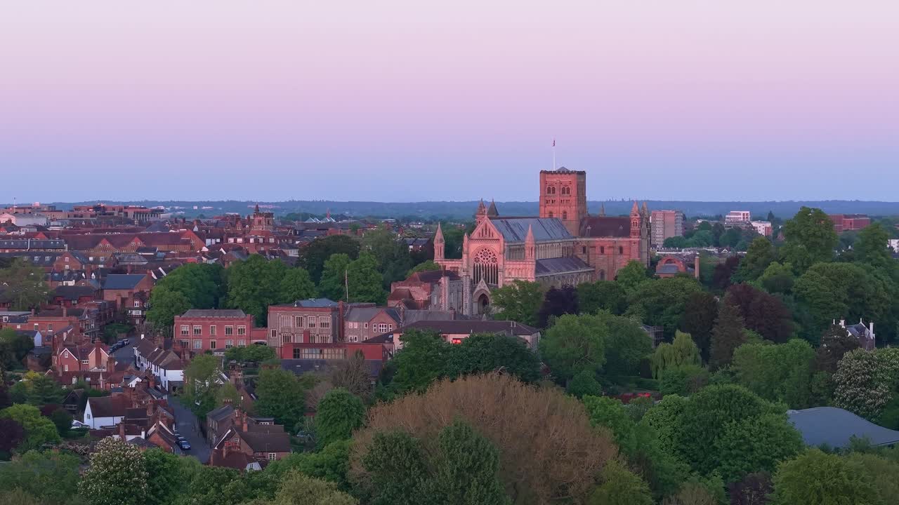 A cinematic drone rises above St Albans Cathedral, tilting down to unveil its majestic gothic spires and the surrounding park and cityscape in stunning aerial detail