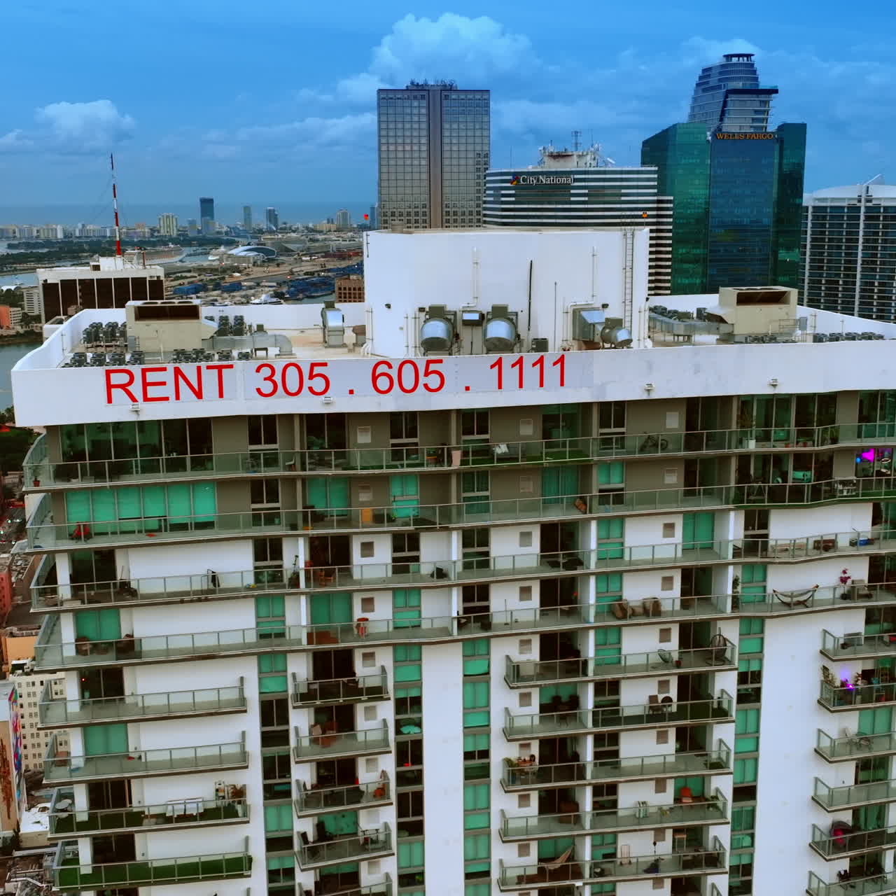 Footage along the top of multi-storied building with a sign of rent. Miami panorama from top view.