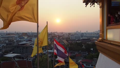 Flying-flags-in-a-Buddhist-temple-Wat-Saket-in-Bangkok,-Thailand-during-sunset