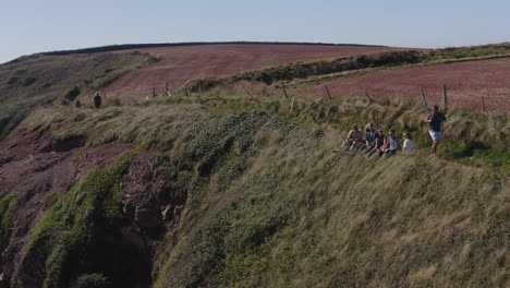 drone shot of group of friends hiking along cliffs on coastal path