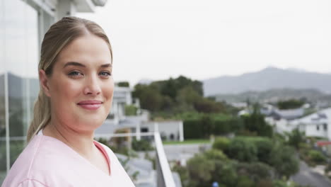 Portrait-of-smiling-caucasian-nurse-on-balcony-with-copy-space,-slow-motion