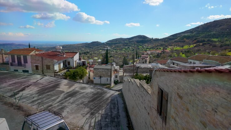 Elevated view over Lefkara, showcasing stone houses and verdant hills, with the expansive Mediterranean landscape stretching into the horizon