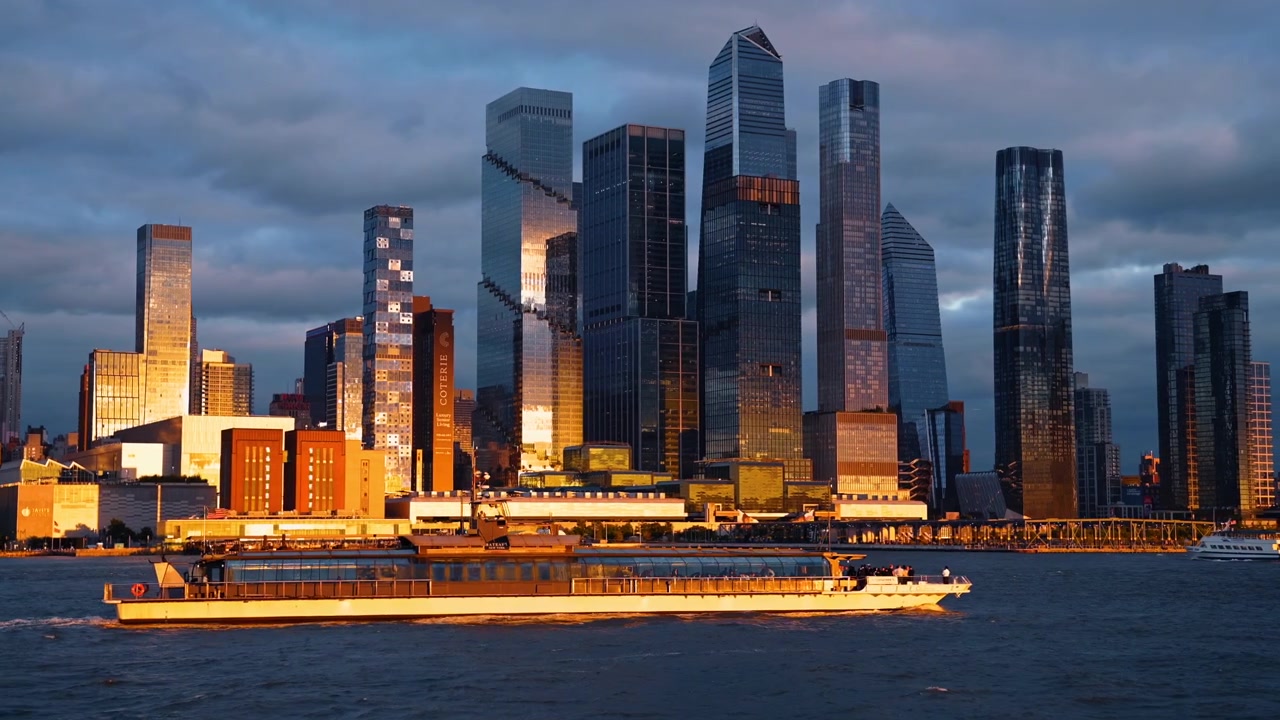 New York, USA, 22 May 2026: Hudson Yards skyscrapers at sunset golden hour New York. Modern glass skyscrapers of Hudson Yards illuminated by golden sunset light with a cruise boat on the river.