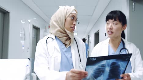 Two-female-doctors-walking-in-corridor-holding-x-ray-4k