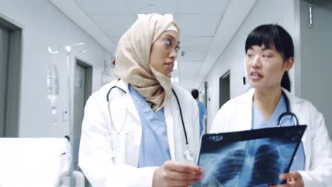 two female doctors walking in corridor holding x-ray 4k