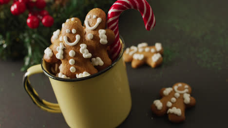 Video-of-cup-with-smiling-gingerbread-men-over-black-background