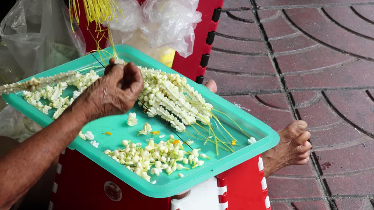 손으로 전통적인 재스민 꽃의 꽃줄을 만드는 것