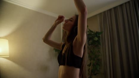 movimiento lento de una joven feliz en auriculares bailando y moviéndose en sostén
