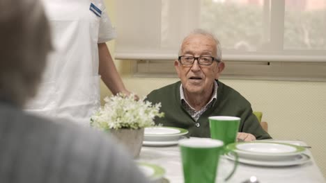 Senior man looking away while sitting at dining table of nursing home