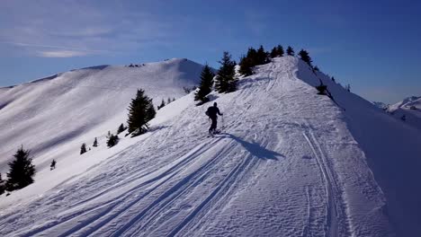 drone following skiier skinning on mountain ridge