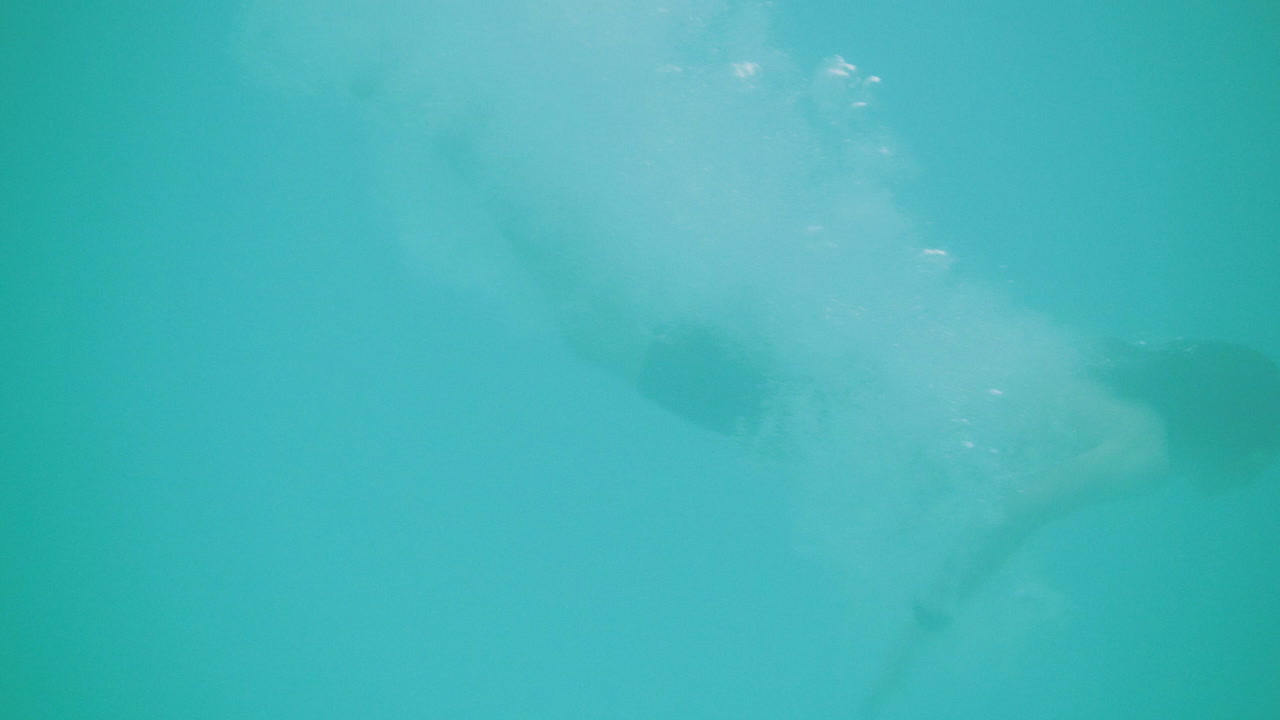 macho joven salta a la piscina y se sumerge