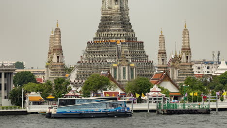 wat arun temple in bangkok, thailand with longtail boats