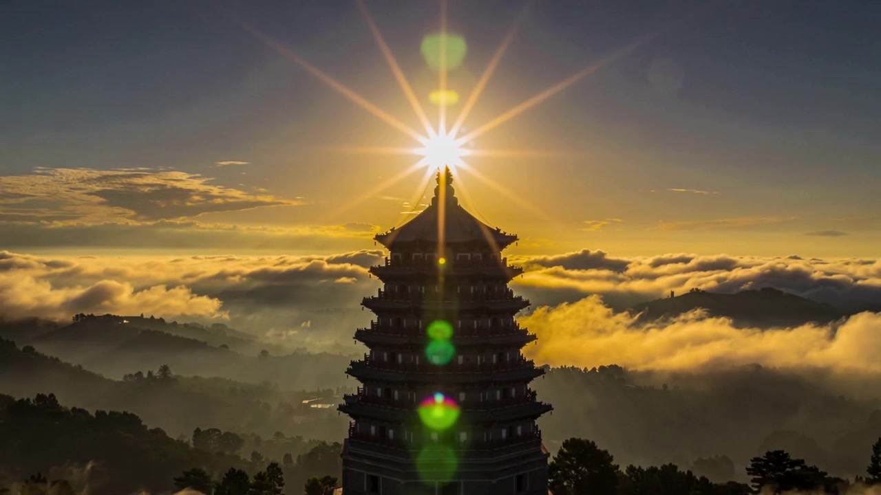Mặt trời mọc tạo thành vệt sáng hình sao phía trên đỉnh tháp chùa nhiều tầng trên sườn núi, tạo ra các vệt lóa ống kính màu xanh lục.