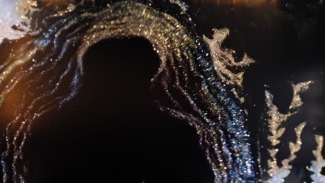 swirling dark liquid with shimmering gold particles in an abstract macro view, cosmic feel