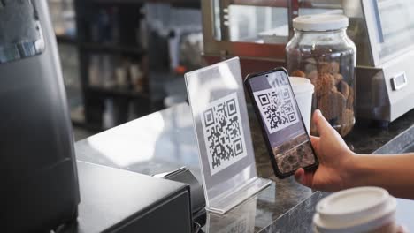 caucasian customer scanning qr code with smartphone in bakery in slow motion