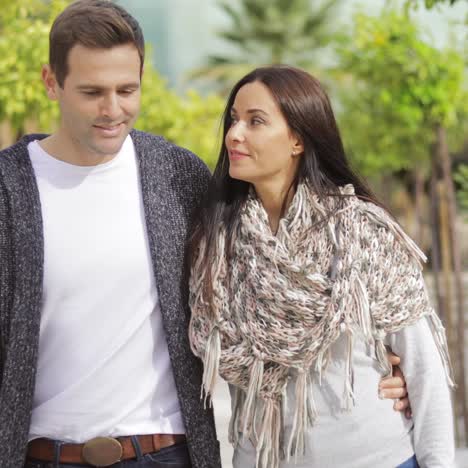 Trendy-young-couple-walking-along-a-promenade