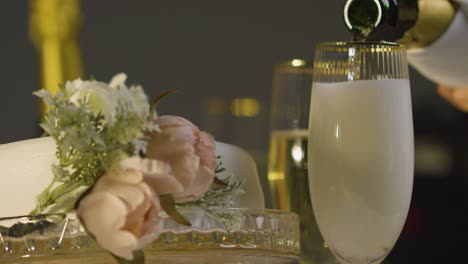 close up of person pouring champagne into glass at table set for meal at wedding reception 3