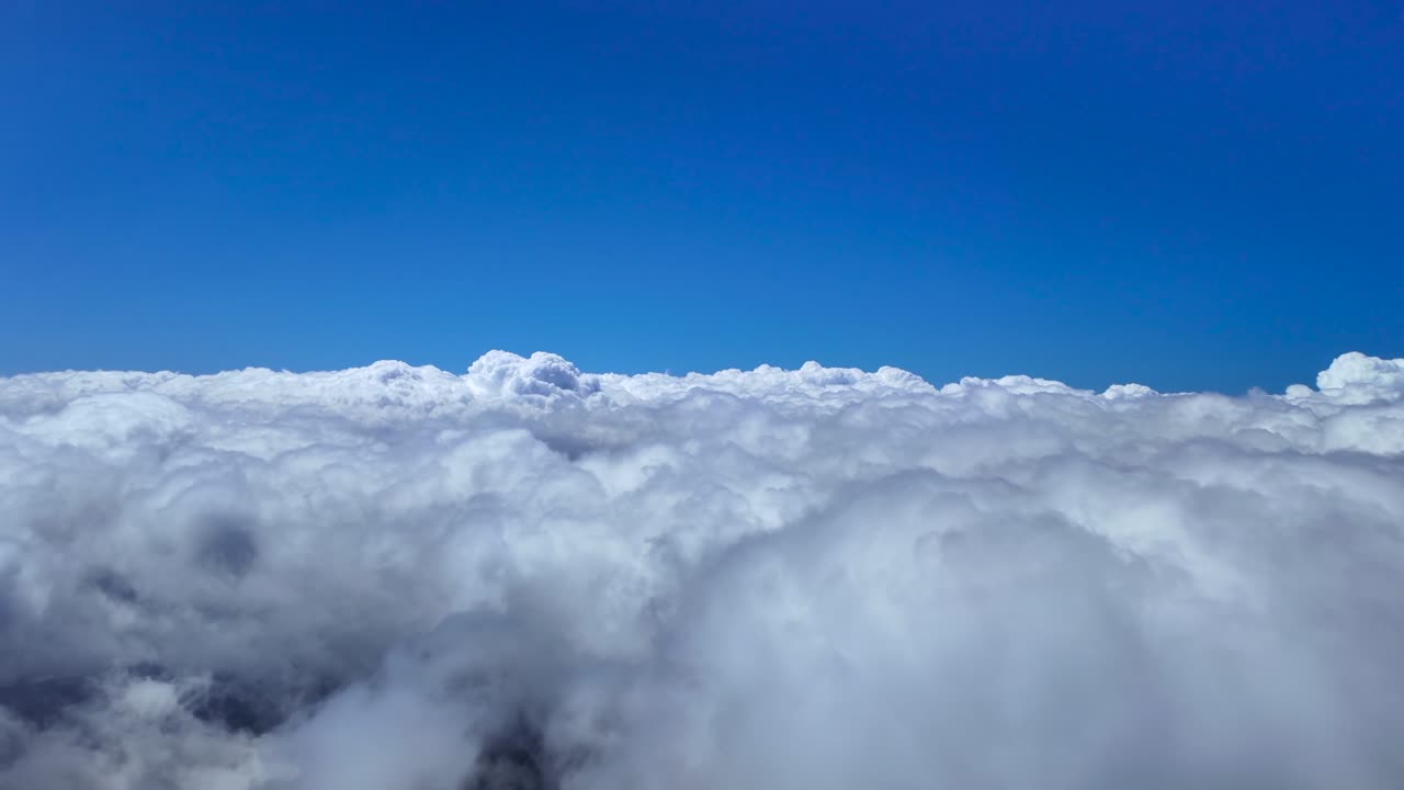 A pilot’s perspective from a jet cockpit while flying peacefully over and endless sea of stratus clouds, under a deep blue sky