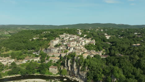 aerial flying towards balazuc village, passing over ardeche river, france