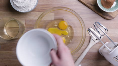 una mujer vierte huevos en un recipiente de vidrio, haciendo pastel de zanahoria casero