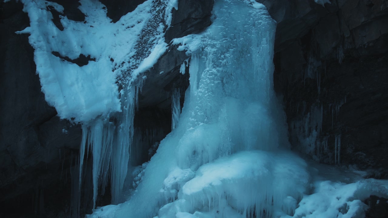 Stream flowing under frozen waterfall