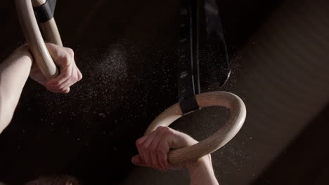 closeup slomo of blond male athlete doing pull up in gym with gymnastic rings