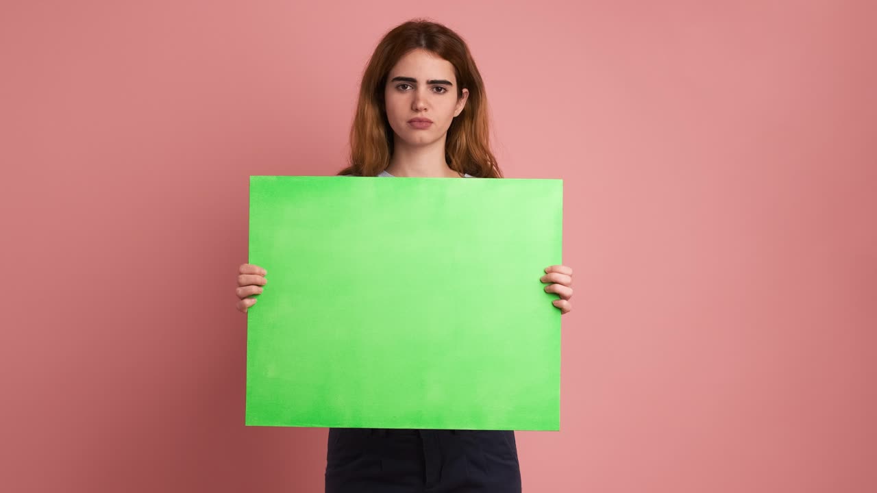 Young woman worried and upset holding a green panel