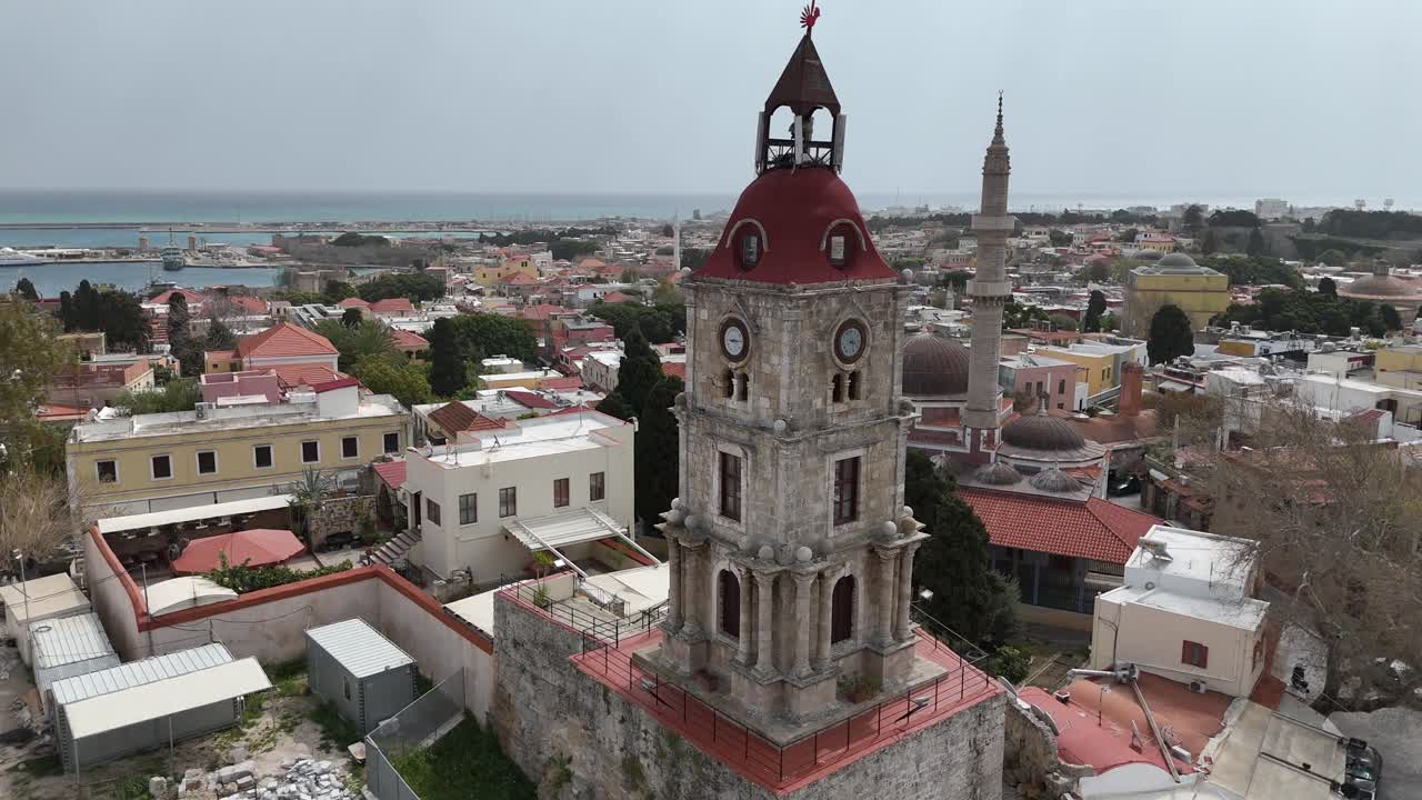 Aerial view backwards from the Medieval Clock Tower (Roloi Clock Tower) and The Suleyman Mosque in the city of Rhodes in Rhodes island in Greece.Harbor and old town at the background on a sunny day.