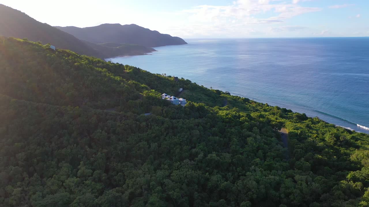 This sunlit aerial footage showcases the turquoise sea and forested coast near St. Croix, USVI, where a handful of upscale vacation villas are elegantly secluded in the lush greenery