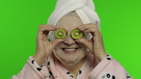 Ältere-Großmutter-Im-Bademantel-Mit-Blasen-Gesichtsmaske.-Alte-Frau-Mit-Kiwi