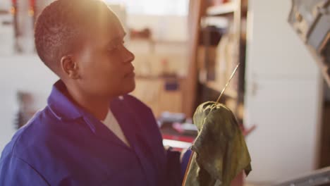 Video-of-african-american-female-car-mechanic-checking-oil-level