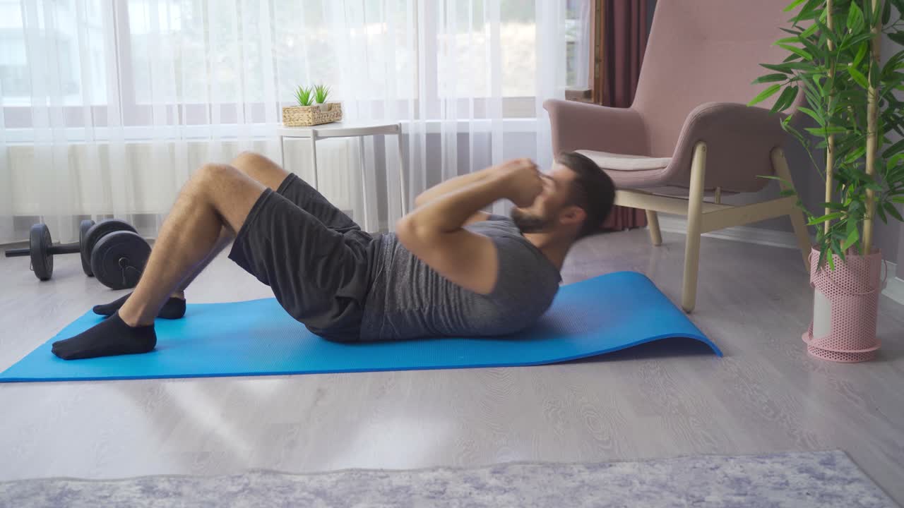 Uomo forte, atletico e in forma in maglietta e pantaloncini che si allena a casa