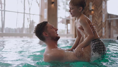 happy preschooler boy is playing with his dad in swimming pool family is resting together in weekend or vacation