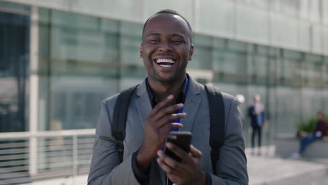 Retrato-De-Un-Joven-Empresario-Afroamericano-Parado-En-La-Calle-Hablando-Riendo-Usando-Negocios-Corporativos-De-Teléfonos-Inteligentes