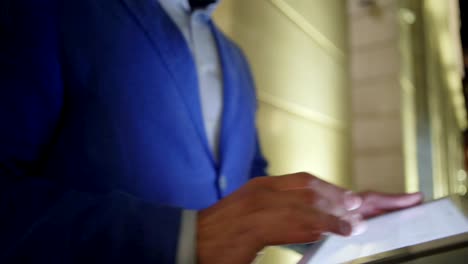 side view tracking shot of unrecognizable businessman using tablet pc while walking down street in evening, closeup
