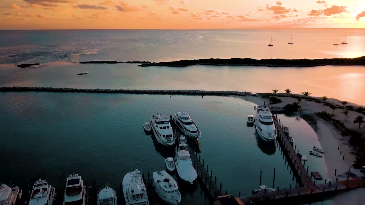 Yacht privati ancorati in una baia delle Bahamas al tramonto, ripresa in allontanamento.