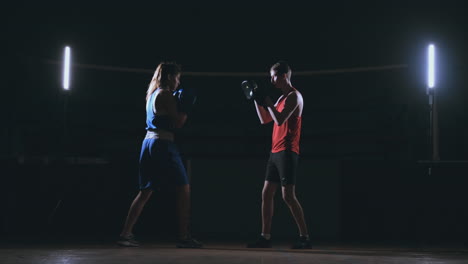 Female-boxer-punching-a-focus-mitts-with-boxing-gloves-in-a-smoky-gym