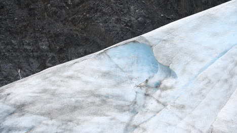 glacier surrounded by black rock in alaska