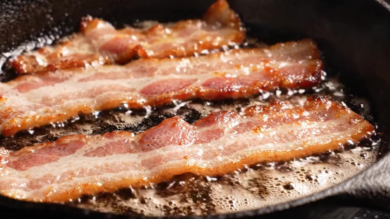 Pancetta sfrigolante: uno sguardo ravvicinato a deliziose striscioline che cuociono in una padella con oro unto e aromi saporiti che riempiono l'aria.