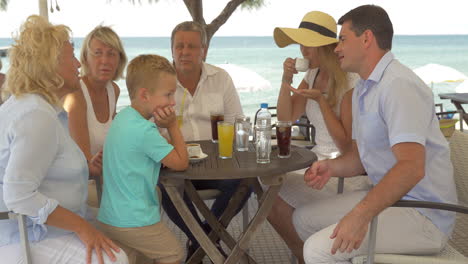 big family sitting at table on the sea coast in city of perea greece