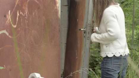 Woman-peeking-inside-old-abandoned-building-door