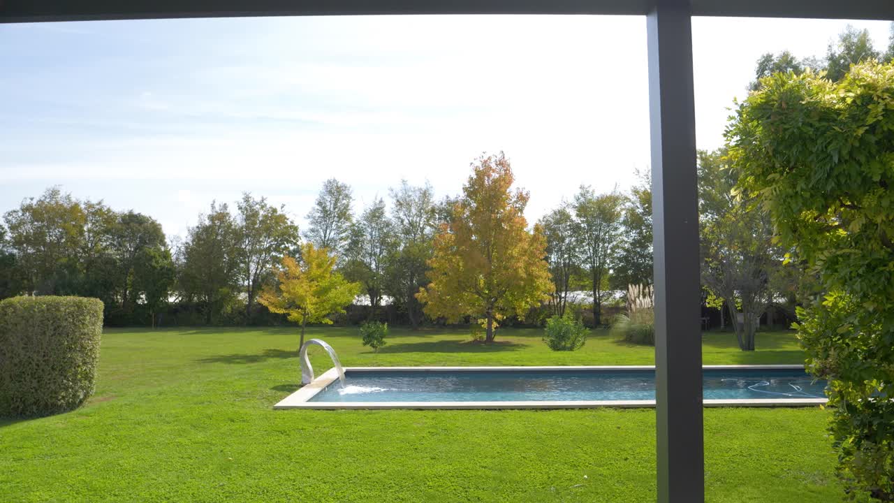Carrellata al rallentatore verso una piscina privata in un giardino che si sta riempiendo