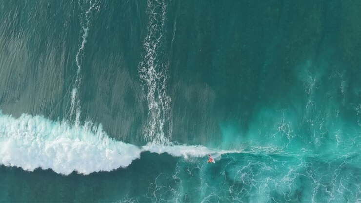 Aerial top down view of surfers catching ocean waves