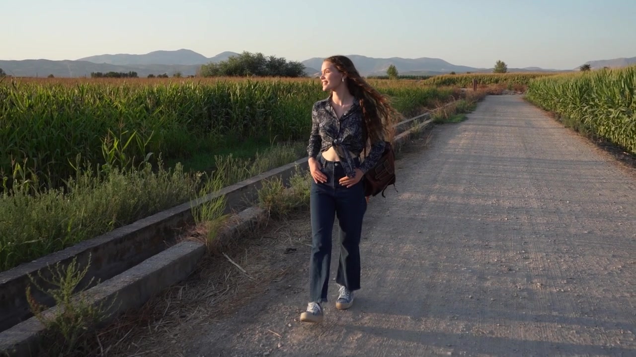 A young woman strolling along a picturesque agricultural path surrounded by natures beauty