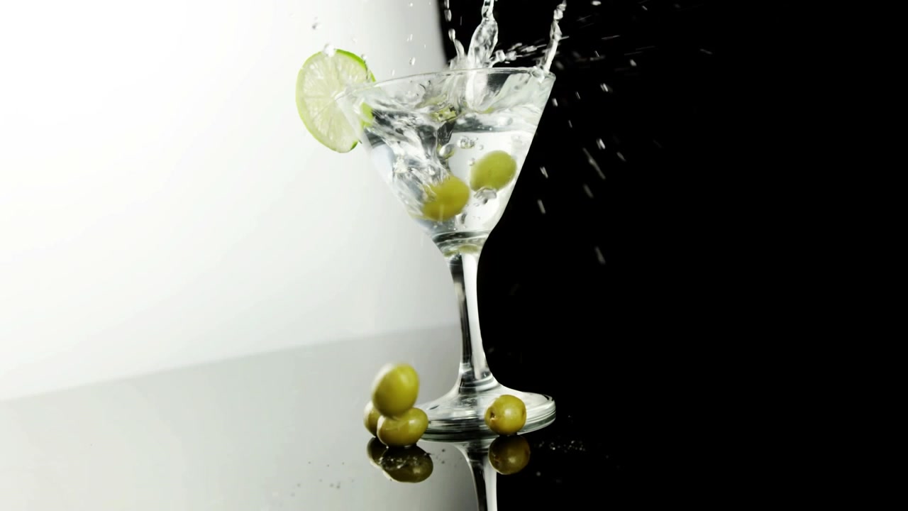 Video di olive che cadono in un bicchiere di martini su sfondo bianco e nero
