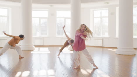 multiethnic group of contemporary dancers dancing and moving around the studio