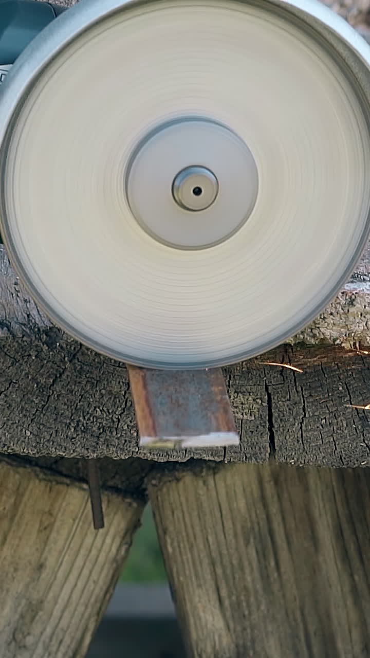 slow motion close view piece of metal plank cut by modern disk saw at old wooden table outdoors